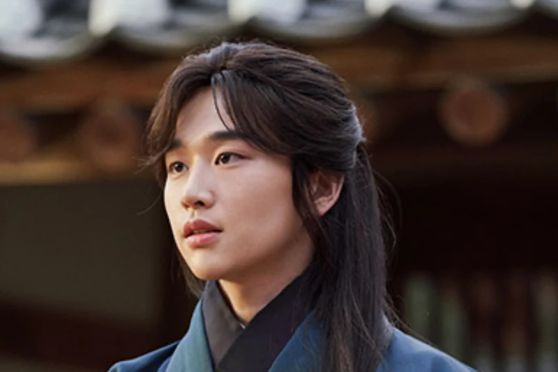 어느 한옥을 배경으로 긴머리에 남색 한복을 입은 드라마 연인의 량음을 연기하는 배우 김윤우